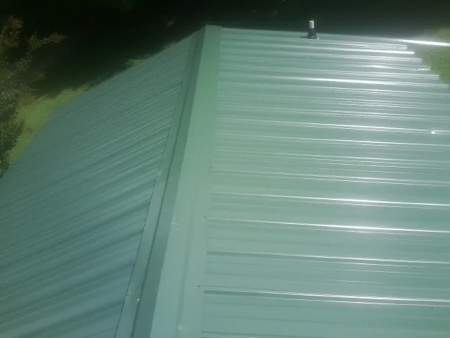 New green metal panels meeting at the ridge of a roof — Flat Roof Repair work by our crew in Llano
