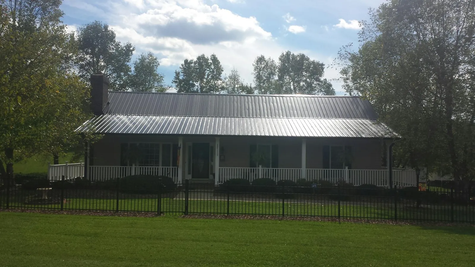 Gray metal roof on a brick ranch with a full width front porch — Gutter Guard Installation work by our crew in Llano