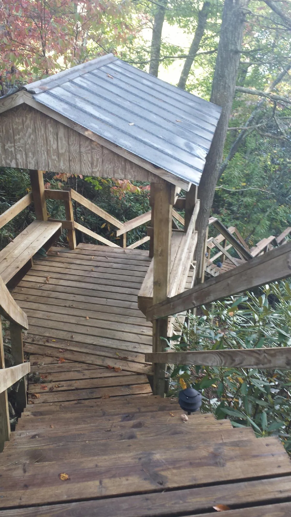 Metal roofed shelter over wooden steps on a wooded walkway — Skylight Repair & Installation work by our crew in Llano