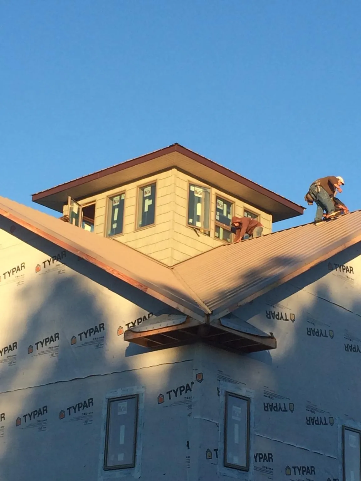 Roofers working around a rooftop cupola on a new metal roof at sunset — Roof Waterproofing in Llano by Roofing Brothers